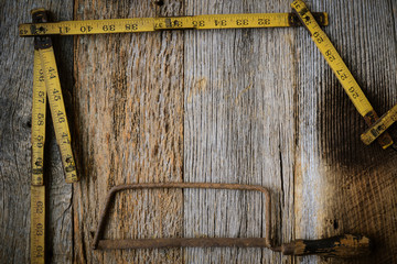 Old Tape Measure and Saw for Construction on Rustic Wood Backgro