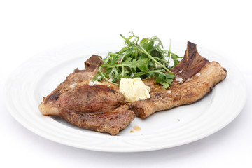 Pork T-bone steak, butter, and salad on plate.