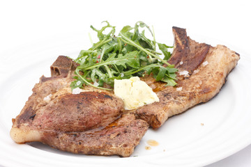 Pork T-bone steak, butter, and salad on plate.