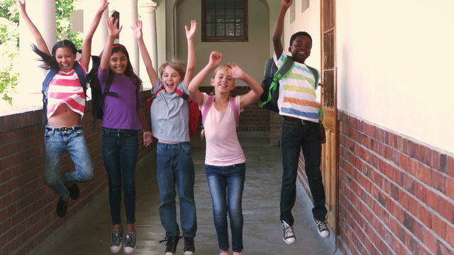 Happy pupils jumping in the air in a hallway