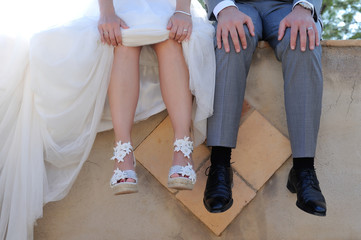 Fototapeta na wymiar feet of bride and groom sitting on a concrete wall