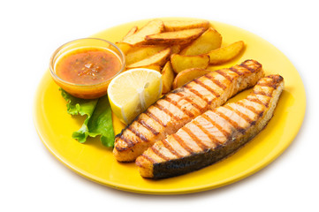 Grilled salmon steak with potatoes and sauce on a yellow plate