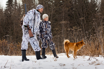 le chasseur avec son fils et leur chien à la chasse hivernale