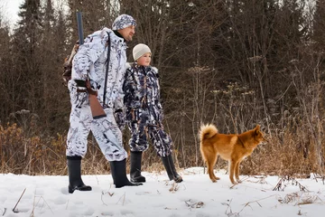 Crédence de cuisine en verre imprimé Chasser le chasseur avec son fils et leur chien à la chasse hivernale