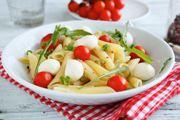 Pasta with vegetables and slices of mozzarella cheese in a plate