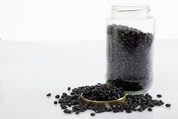 Black beans in a jar on white  table with lid off