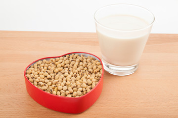 Soy milk in glass with soybeans in heart shape box