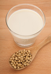 Soy milk in glass with soybeans and wooden spoon