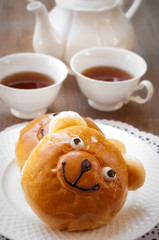 Sweet bun and cup of tea on wooden table