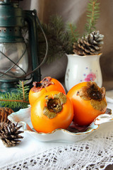Christmas still life with persimmons and pine cones.