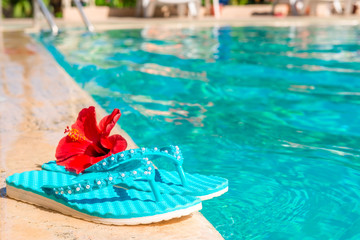 turquoise flip flops and flower on the edge of the pool
