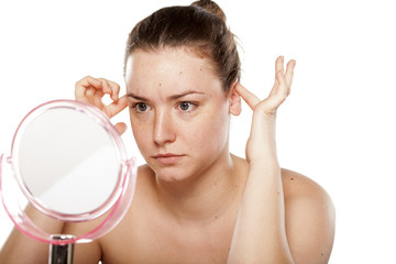 woman looking at herself in the mirror and squeeze her ears