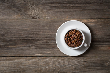 Coffee cup with roasted coffee beans on wooden table. Top view