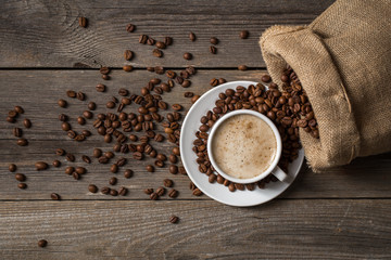 White coffee cup with opened bag. Mug standing on wooden table. 