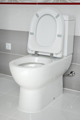 Toilet bowl against a white tile in the bathroom