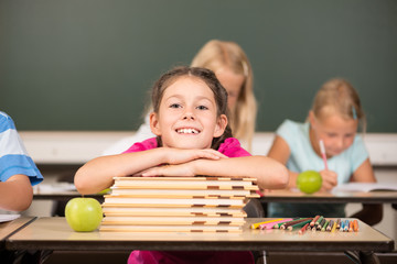 Mädchen auf Bücherstapel in der Grundschule