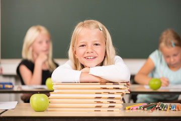 Mädchen auf Bücherstapel in der Grundschule