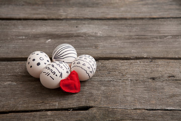 Easter eggs and red heart on wooden background