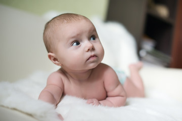 The surprised baby lying on white towel