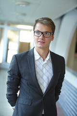young businessman with glasses standing in the hallway