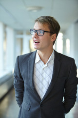 young businessman with glasses standing in the hallway