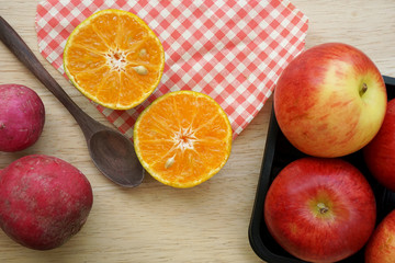 Apples, orange, radish on wooden table