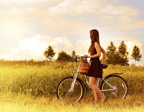 beautiful girl riding bicycle in a grass field