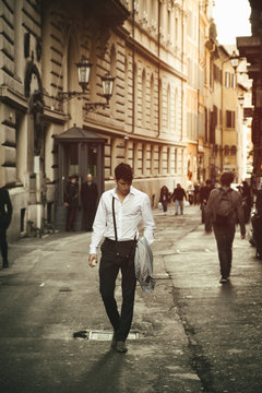 Fototapeta Handsome young man walking in European city street