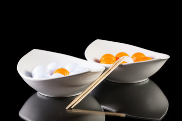 Two white ceramics bowls with golf balls on the glass table