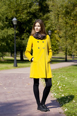 Happy woman in yellow coat walking autumn street