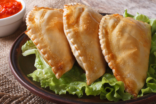 empanadas on a plate with lettuce and sauce closeup.