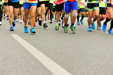 marathon athletes legs running on city road