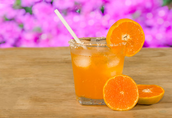 Glass of orange juice and fresh orange  on wooden table,pink bok