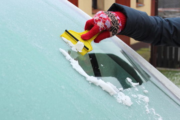 Hand of woman scraping ice from car windscreen - obrazy, fototapety, plakaty