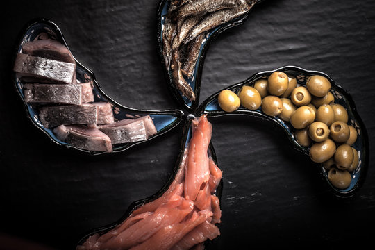 Fish assortment and olives on magic plates on a dark background