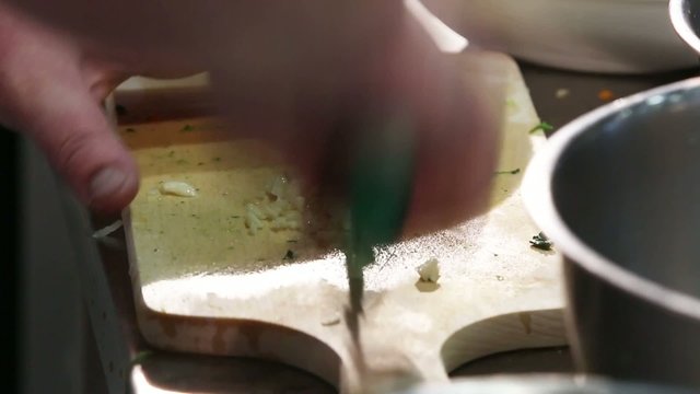 Cook cutting garlic on a chopping board