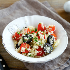 couscous salad with vegetables and olives in white plate