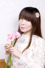 Fototapeta premium 白壁の前でガーベラの花を持つ女性