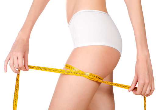 Young, slim female body showing hands while measuring thigh widt