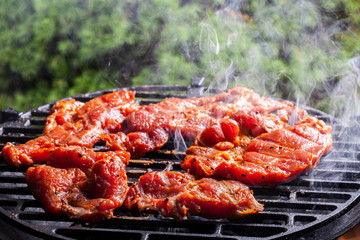 Grilling pork steaks on barbecue grill