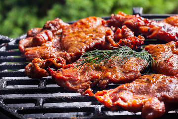 Grilling pork steaks on barbecue grill