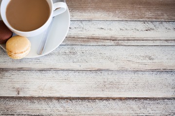 Coffee and macarons on wooden table, with empty place