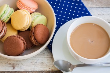 Cup of coffee with milk and macarons on wooden table