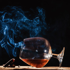 Glass of alcohol and smoking noble cigar on a black background