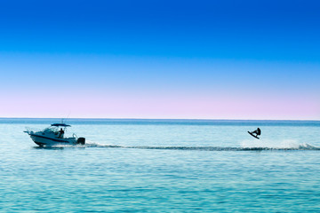 silhouette of motor boat and wakeboarder jumping crazy trick