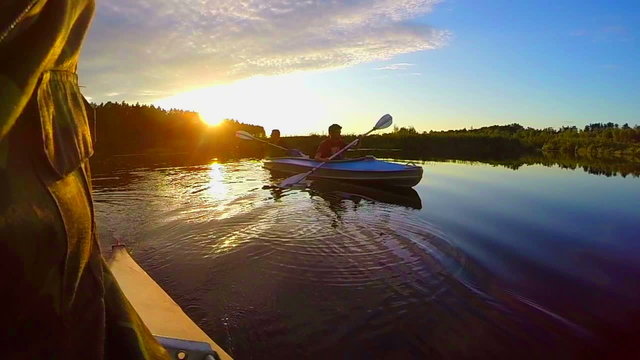 Silhouettes of two males kayaking at sunset, active rest, slowmo