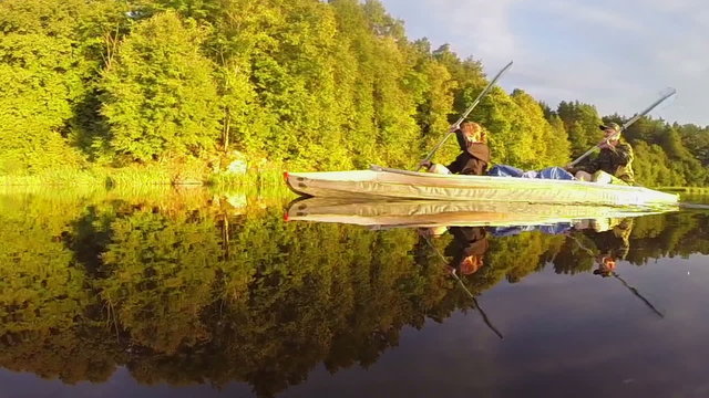 Man and woman paddling canoe synchronously on beautiful river