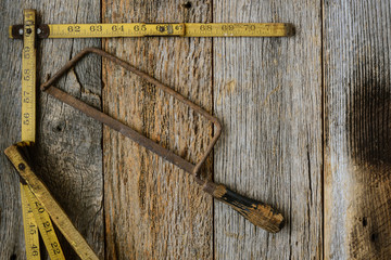 Old Tape Measure and Saw for Construction on Rustic Wood Backgro
