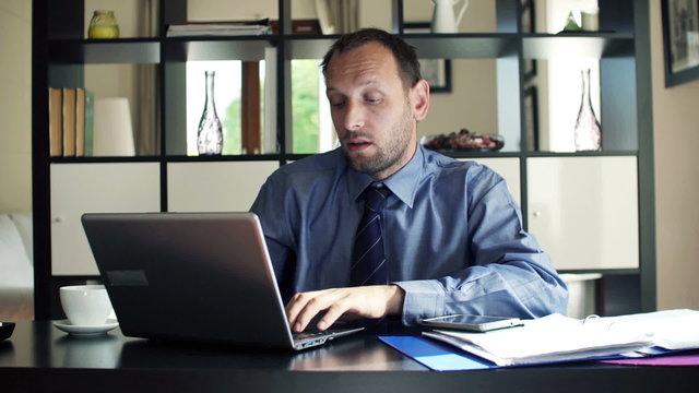 Young businessman talking bad news to camera sitting by desk