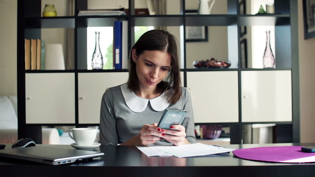 Businesswoman working with smartphone by the desk at home